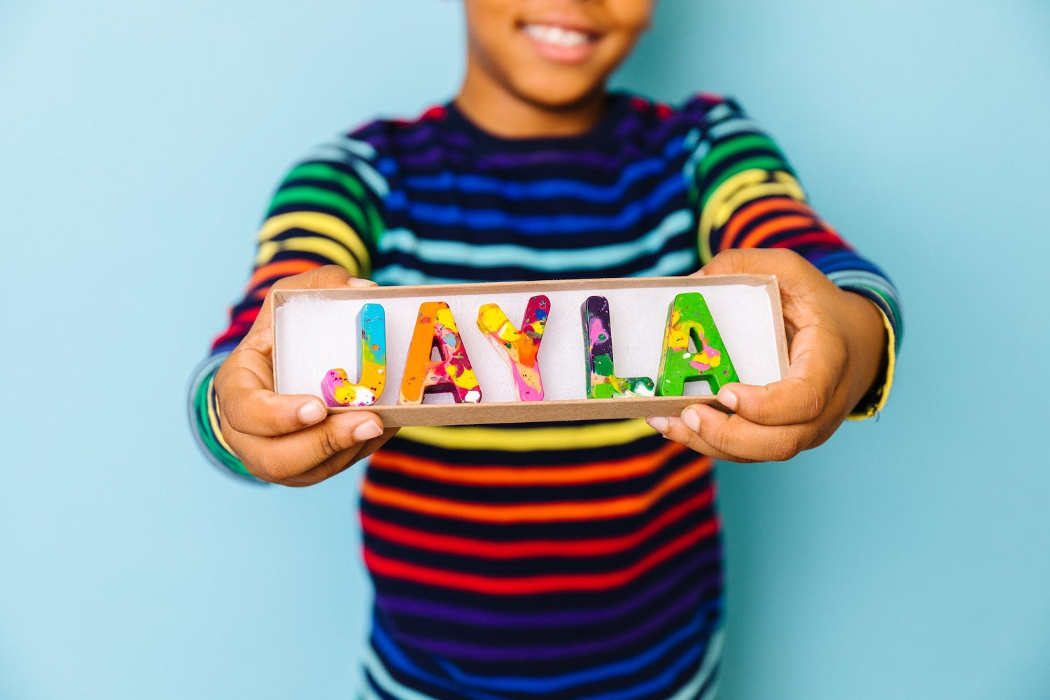 Crayon image is of a child holding a box of rainbow crayon letters that spell JAYLA.  With convenient options like ShopPay Buy and Cart Buy, adding these delightful crayons to your cart and completing your checkout is a breeze. 
