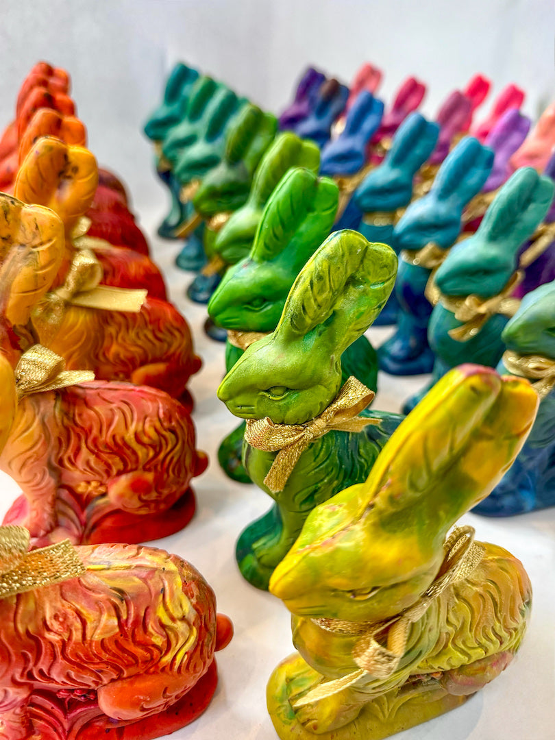 A colorful assortment of Easter Bunny crayons for kids, handcrafted in a rainbow of vibrant hues, each tied with a gold ribbon. These handmade bunny-shaped crayons make perfect Easter basket fillers, party favors, and unique gifts for little artists. Displayed in neat rows, the multicolored crayons offer a fun and creative alternative to traditional Easter treats.